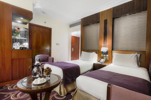 a hotel room with two beds and a table at Elaf Kinda Hotel in Makkah