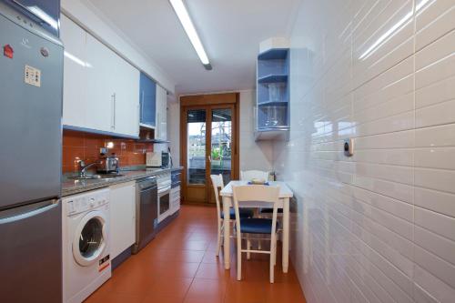cocina con mesa, fregadero y lavavajillas en Apartamento de La Casona de Riomera, en Oviedo