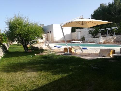 a pool with an umbrella and a chair and a table at Dimora Il Mandorlo in Ostuni