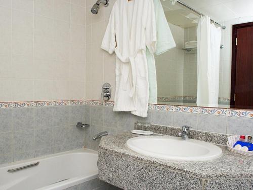 uma casa de banho com um lavatório, uma banheira e um espelho. em Safeer Plaza Hotel em Mascate
