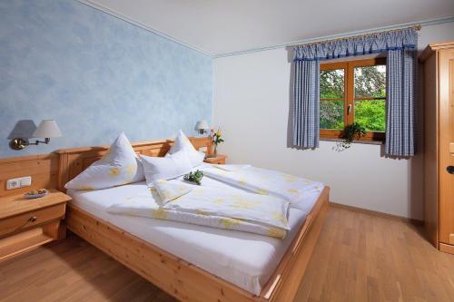 a bedroom with a bed with white sheets and a window at Ferienwohnungen Zweckl in Marktschellenberg