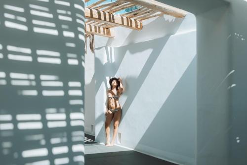 a woman in a bikini standing in a white wall at Mykonos Blanc - Preferred Hotels & Resorts in Ornos