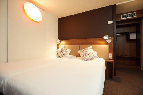 um quarto com uma grande cama branca e 2 almofadas em Campanile Pau Est-Bizanos em Pau