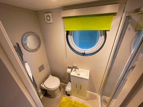 a small bathroom with a toilet and a window at Lady Florence, Maidstone a Unique River Boat with Castle Views in Kent