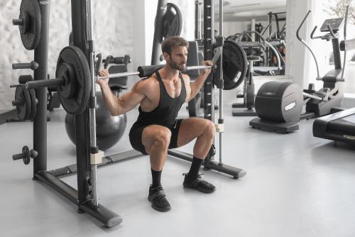 a man squatting in a gym lifting weights at Mykonos Blanc - Preferred Hotels & Resorts in Ornos