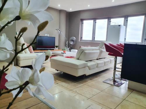a living room with a white couch and a tv at Franklin L Apartment in Johannesburg