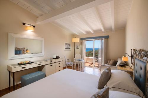 a bedroom with a bed and a desk with a view at CPH | Pevero Hotel in Porto Cervo