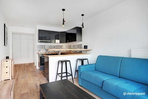un salon avec un canapé bleu et une cuisine dans l'établissement Cozy apartment - 1BR-4P - next to Paris, à Levallois-Perret