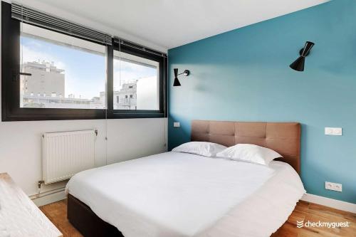 Un dormitorio con una cama grande con una ventana grande. en Cozy apartment - 1BR-4P - next to Paris, en Levallois-Perret