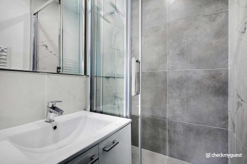Un baño blanco con lavabo y ducha. en Cozy apartment - 1BR-4P - next to Paris, en Levallois-Perret