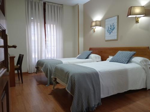 a hotel room with two beds and a window at Hotel Los Robles in Cangas de Onís