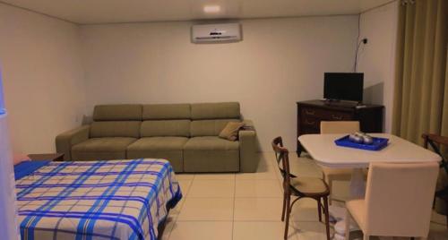 ein Wohnzimmer mit einem Sofa, einem Bett und einem Tisch in der Unterkunft Flat Deluxe2 Gramado in Gramado
