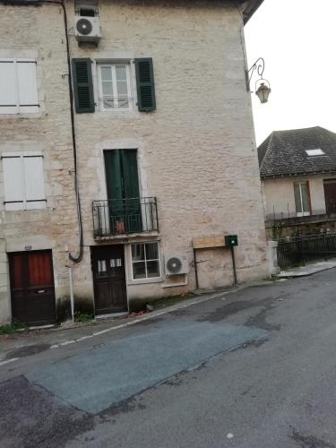 a brick building with a green door and balcony at L'éden Quercynois in Souillac