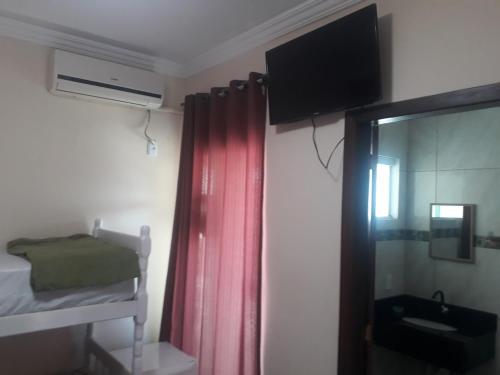 1 dormitorio con litera y TV en la pared en Pousada Ilha do Itacolomi, en Penha