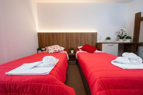 two beds in a room with red sheets and towels at Gostilna Pugelj in Novo Mesto