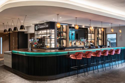 a bar with red seats at a restaurant at Holiday Inn London-Shepperton by IHG in Shepperton