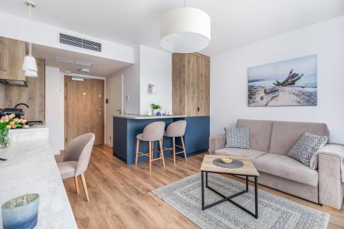 a living room and kitchen with a couch and a table at Apartamenty Jantaris II by Renters in Mielno