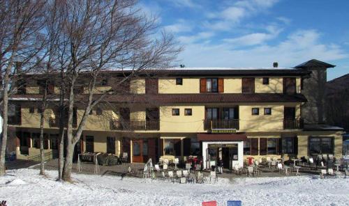 a large building with tables and chairs in front of it at Hotel Le Polle in Riolunato