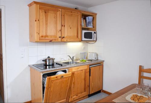 a kitchen with wooden cabinets and a sink at Olydea Fontaine du Roi in Saint-Jean-dʼArves