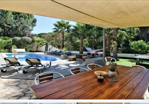 a patio with a wooden table and chairs and a pool at Villa Francisco in Calonge