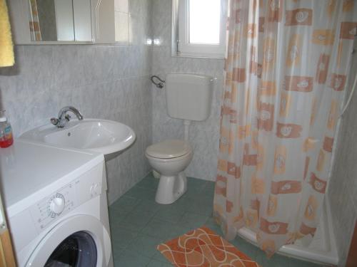 een badkamer met een toilet, een wastafel en een wasmachine bij Apartman f1 in Pula