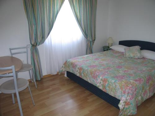 een slaapkamer met een bed, een tafel en een raam bij Apartman f1 in Pula