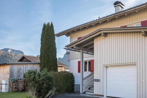 a house with a white garage door in a yard at Wohnung Kanisfluhblick in Bizau