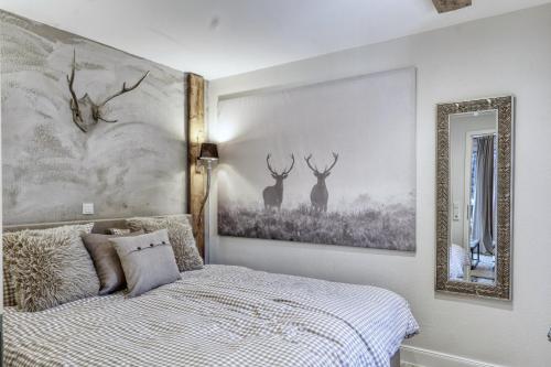 1 dormitorio con 1 cama con pinturas de ciervos en la pared en HOME Suites Deluxe mit Sauna en Braunlage