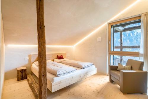 um quarto com uma cama, uma janela e uma cadeira em Ferienhaus im Stadl em San Martino