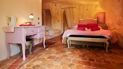 a bedroom with a bed and a dresser and a desk at Logis Hôtels Troglododo in Azay-le-Rideau