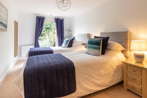 a bedroom with two beds with blue curtains and a window at The Sands Sea Front Apartments in Scarborough