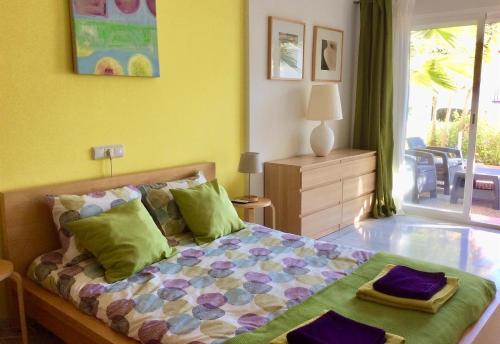 Schlafzimmer mit einem Bett mit grünen und violetten Kissen in der Unterkunft Vista Marina - 2 bedrooms sleeps 4 in La Herradura
