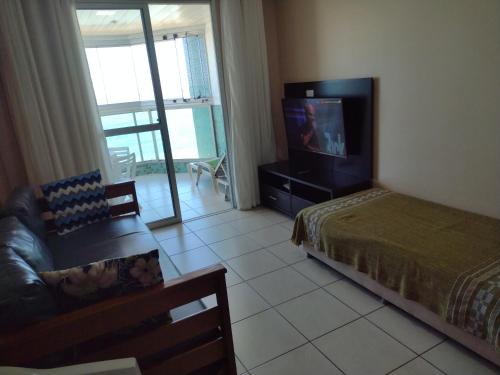 um quarto com uma cama, uma televisão e um sofá em D Frente Green D 2 em Vila Velha
