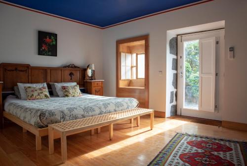 a bedroom with a bed and a bench in it at Quinta da Meia Eira in Horta