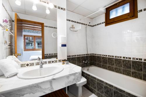 a bathroom with a sink and a tub and a toilet at Apartaments Les Terrasses del Tarter in El Tarter