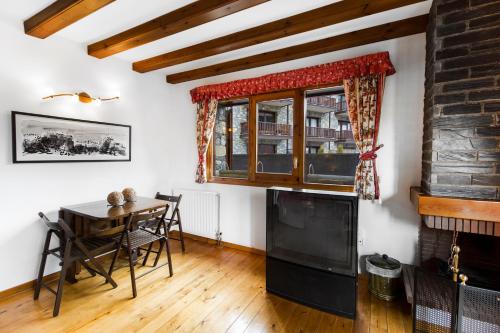 a dining room with a table and a television at Apartaments Les Terrasses del Tarter in El Tarter