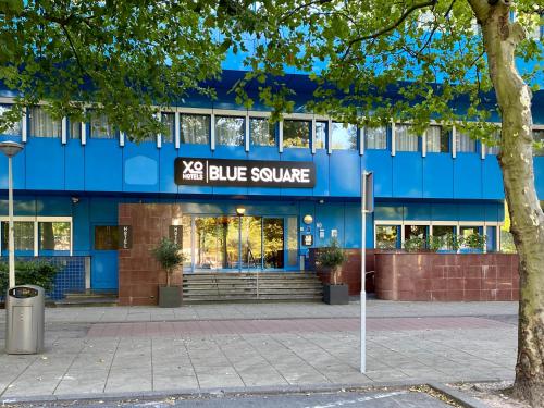 un edificio azul con una señal cuadrada azul delante en XO Hotels Blue Square en Ámsterdam