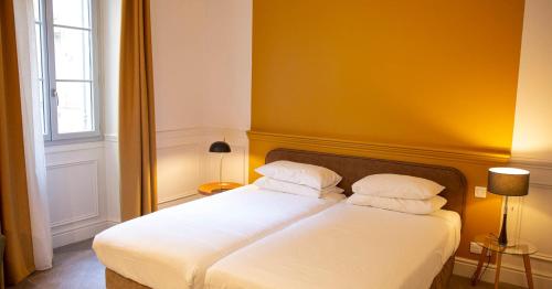 a bedroom with a bed with two white pillows at Hôtel Royal in Montpellier