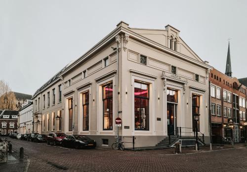 Biały budynek z samochodami zaparkowanymi przed nim w obiekcie The Nox Hotel w mieście Utrecht
