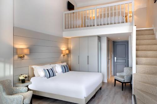 a bedroom with a white bed and a staircase at La Bastide de Biot in Biot