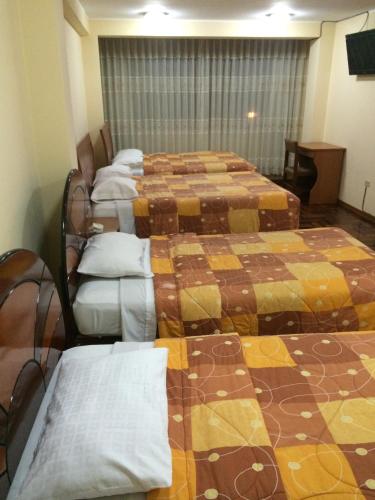 a room with four beds in a row with at Hotel Viña del Mar in Tacna