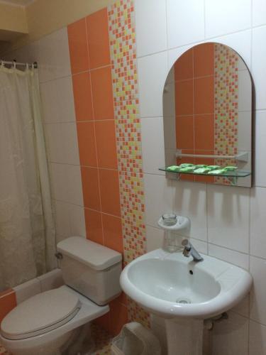 y baño con lavabo, aseo y espejo. en Hotel Viña del Mar, en Tacna