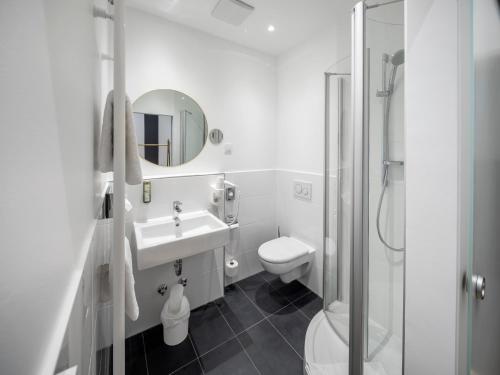 ein Badezimmer mit einem Waschbecken, einem WC und einem Spiegel in der Unterkunft acor Boutique Hotel in Heidelberg