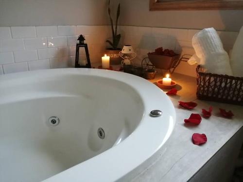 une grande baignoire blanche avec bougies et roses rouges dans l'établissement ALMA Glamping - San Francisco Cund - A 1h de Bogotá, à San Francisco