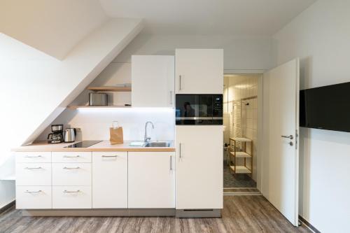 a kitchen with white cabinets and a staircase at Altes Wasserwerk, FW 7 in Zingst