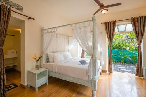 a bedroom with a canopy bed and a window at Moustache Goa Luxuria in Vagator
