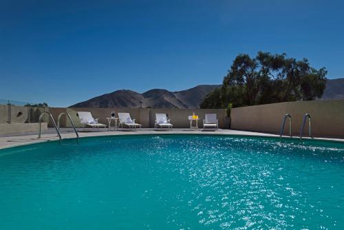 a swimming pool with chairs and mountains in the background at Hotel Atacama Suites in Copiapó