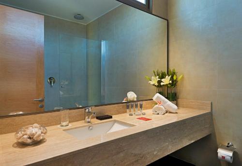 a bathroom with a sink and a large mirror at Hotel Atacama Suites in Copiapó