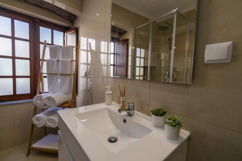 bagno con lavandino bianco e specchio di Barrote Beja- Alojamento Local a Beja
