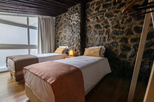 two beds in a room with a stone wall at Barrote Beja- Alojamento Local in Beja